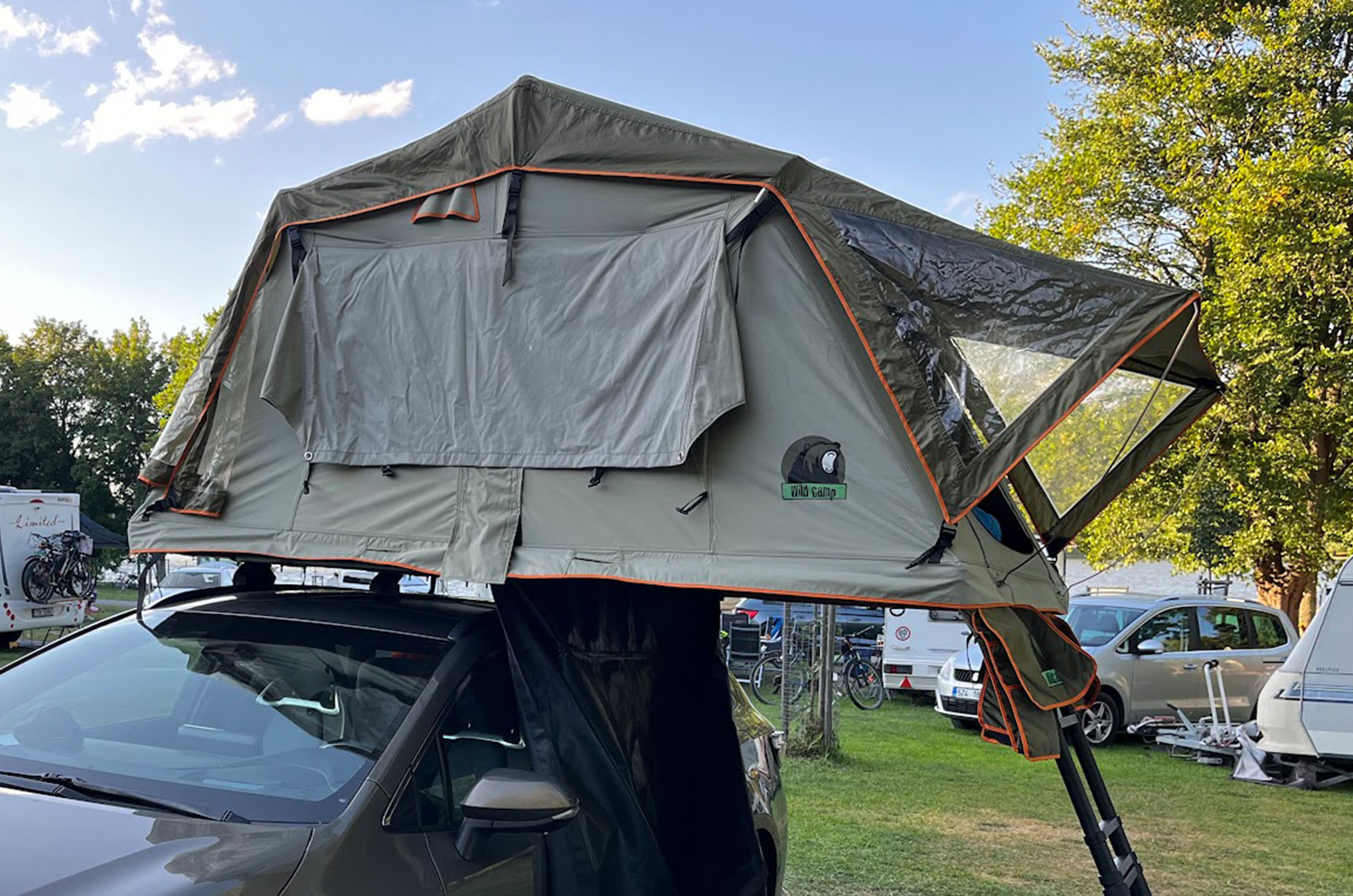 Rozložený střešní stan Wild Camp na autě v kempu